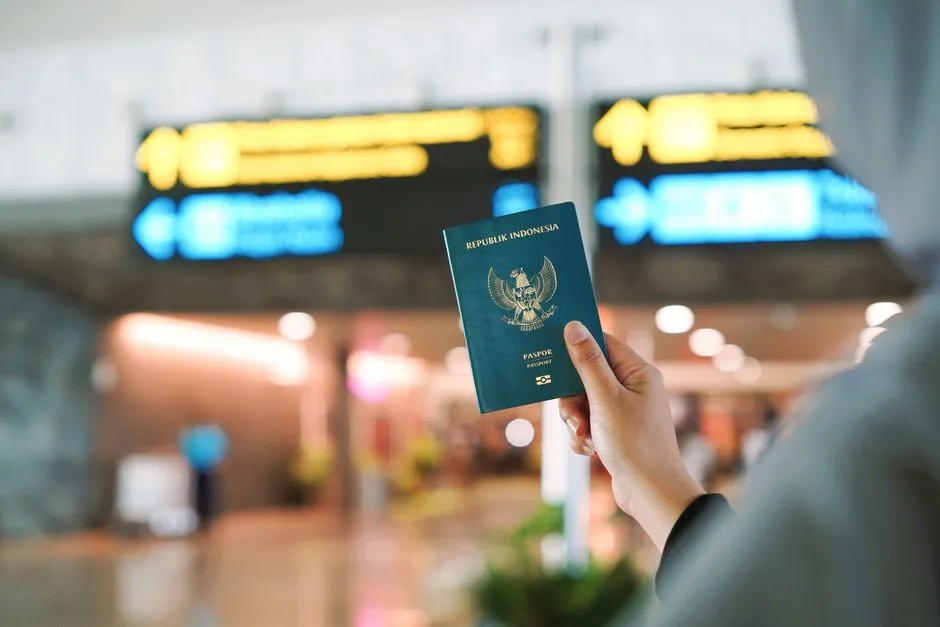 A person holding an Indonesian passport at a busy airport terminal in Yogyakarta, Indonesia.